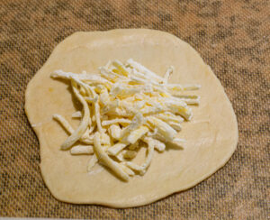 Queso rallado sobre masa de empanada.